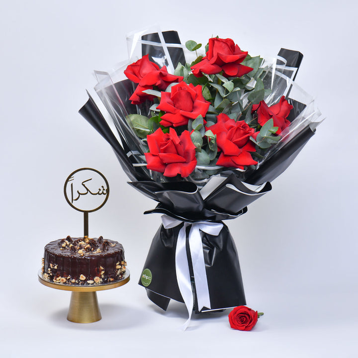 باقة ورود قرمزية أنيقة مع كعكة بالشوكولاتة والبندق
