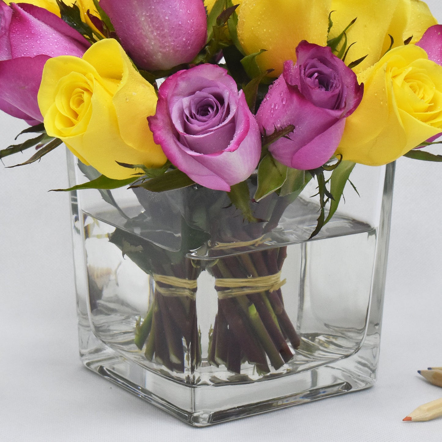 Elegant Arrangement of Yellow and Purple Roses in a Modern Square Glass Vase