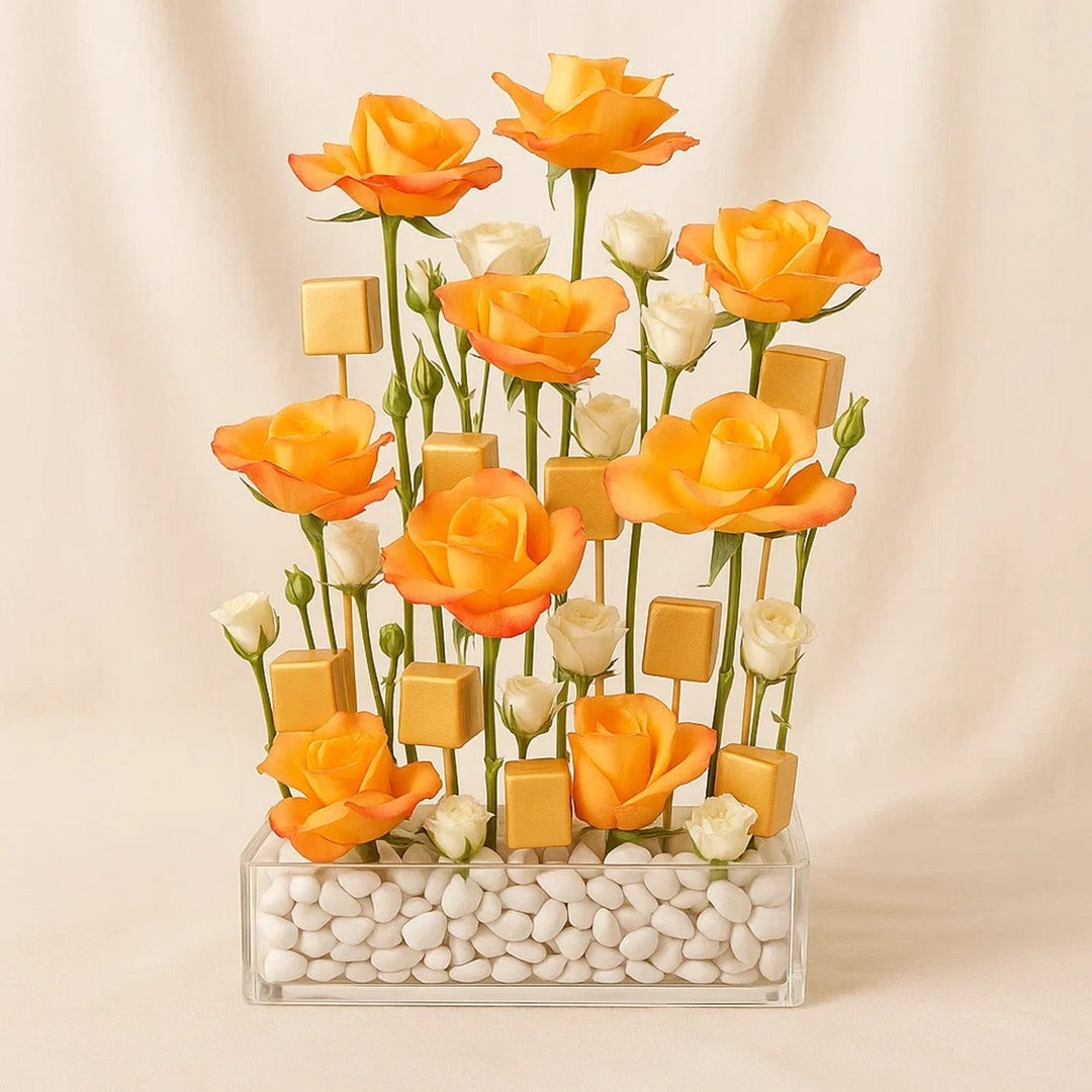 ترتيب أنيق: ورود برتقالية وشوكولاتة ذهبية في مزهرية زجاجية