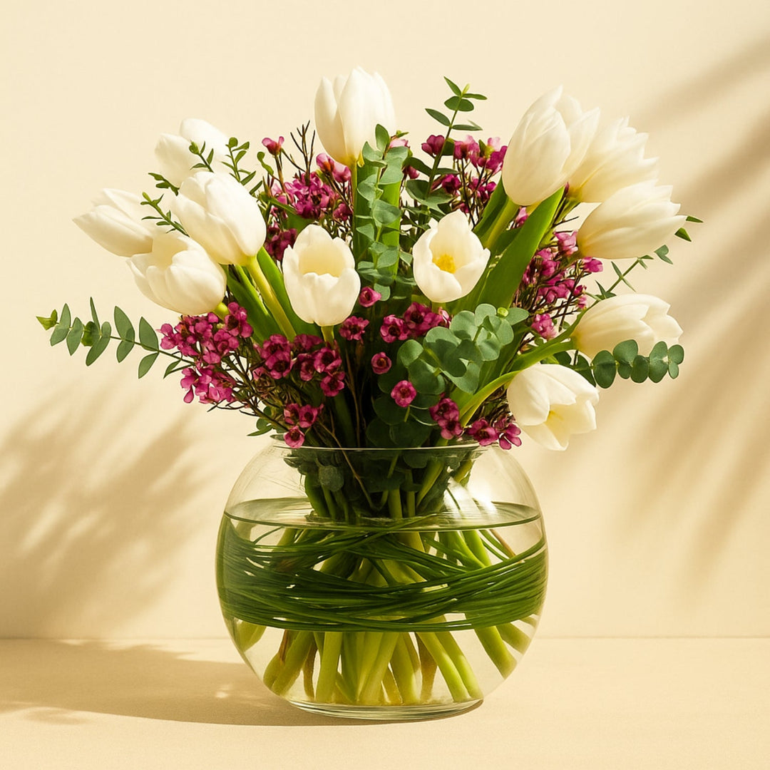 تنسيق أنيق للزهور البيضاء وزهور الشمع في مزهرية زجاجية