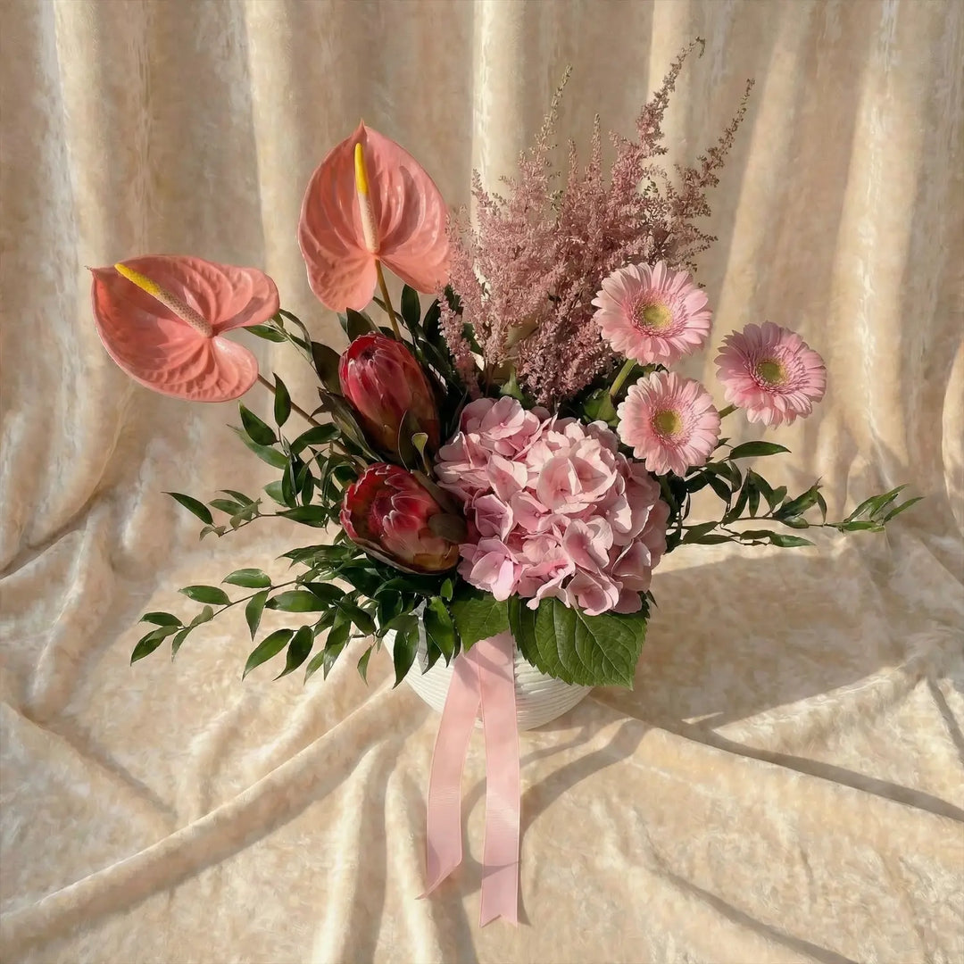 باقة الأنتوريوم والجيربيرا الوردية الأنيقة في وعاء أبيض