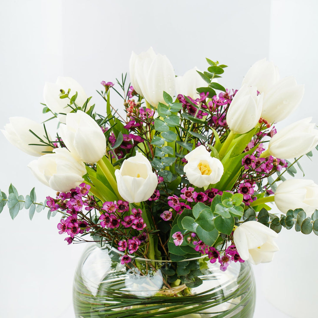 تنسيق أنيق للزهور البيضاء وزهور الشمع في مزهرية زجاجية