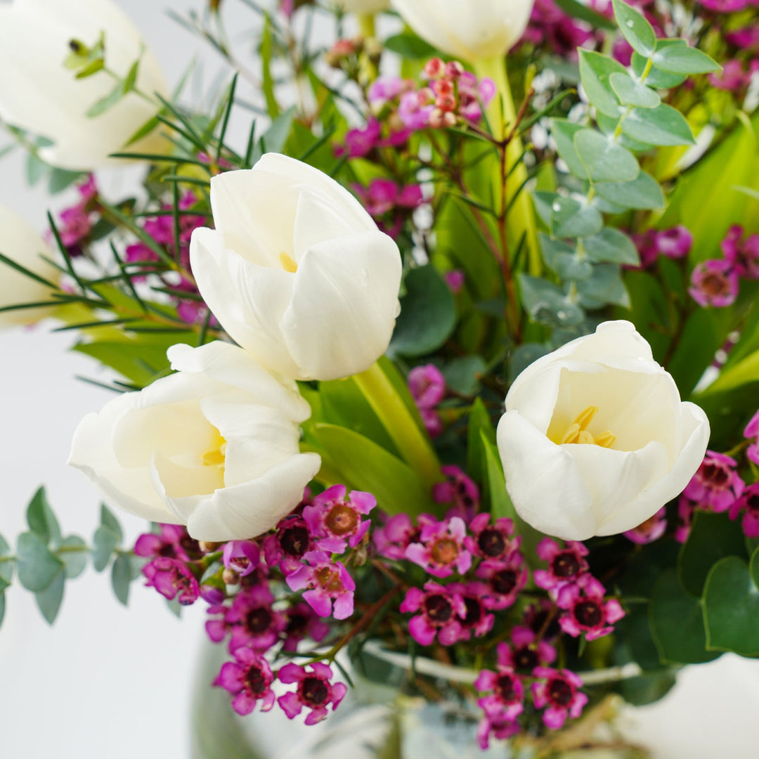 تنسيق أنيق للزهور البيضاء وزهور الشمع في مزهرية زجاجية