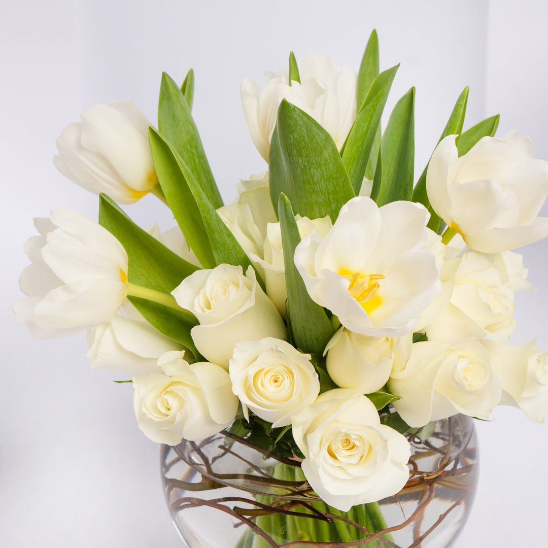 باقة من الورود البيضاء والأزهار في مزهرية زجاجية أنيقة