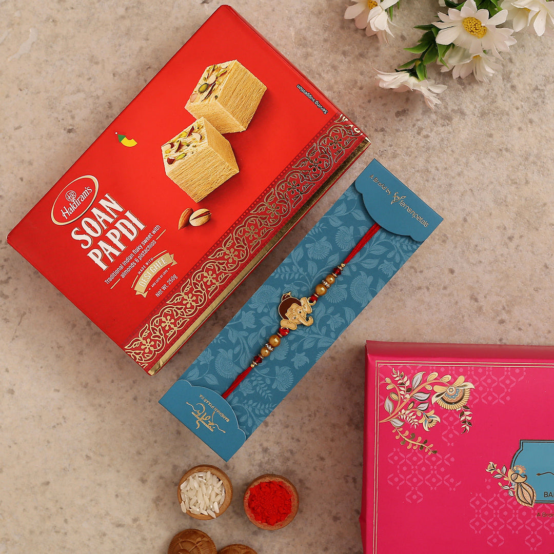 Charming Bal Ganesha Pearl Rakhi for Kids with 250g Haldiram's Soan Papdi Gift Set