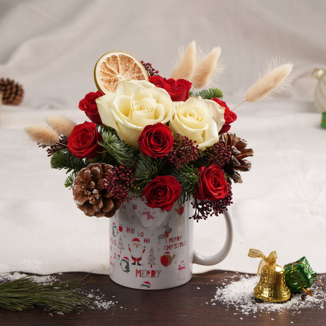 فنجان عيد الميلاد مع ورود حمراء وبيضاء ولمسات موسمية