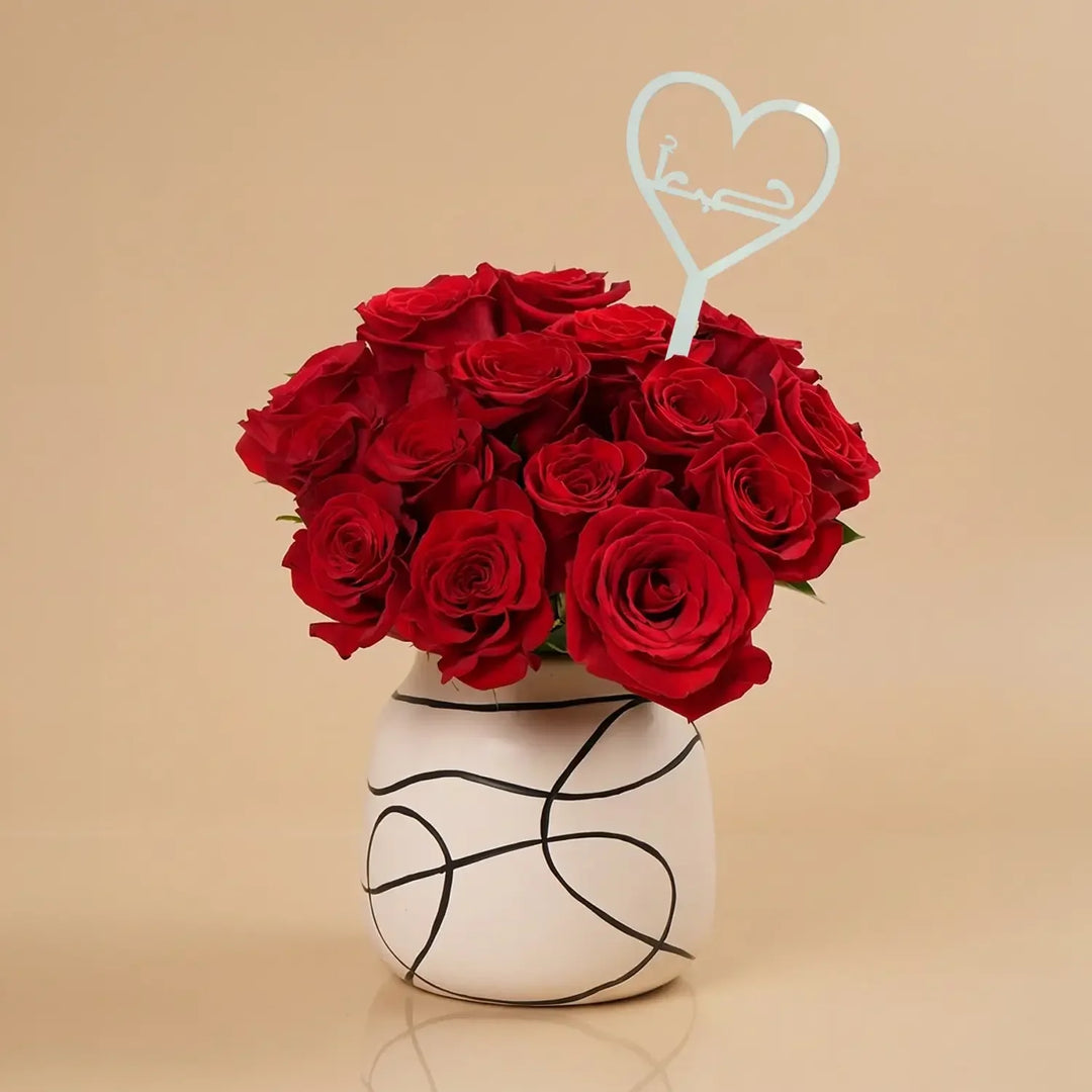 باقة ورد حمراء أنيقة مع مزهرية خزفية ومزينة بحب